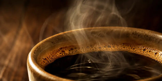 Close-up da borda de uma caneca de cerâmica com café quente, crema e vapor denso