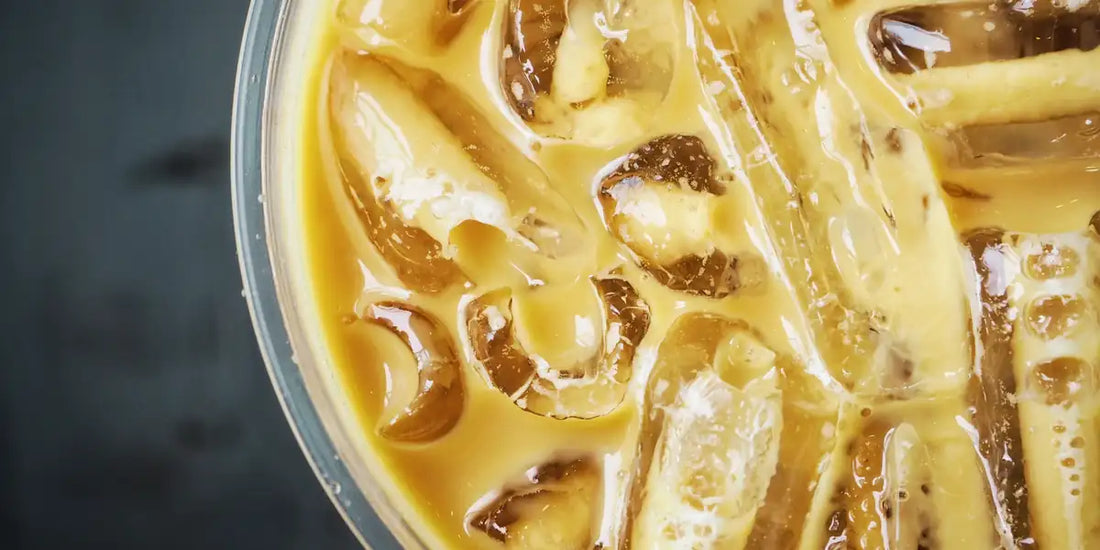 Café gelado com leite e cubos de gelo vistos de cima em copo