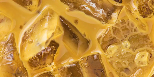 Macro de café gelado cremoso e dourado com cubos de gelo translúcidos e reflexos de luz