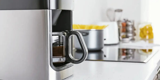 Cafeteira elétrica programável com jarra de vidro sobre bancada de cozinha