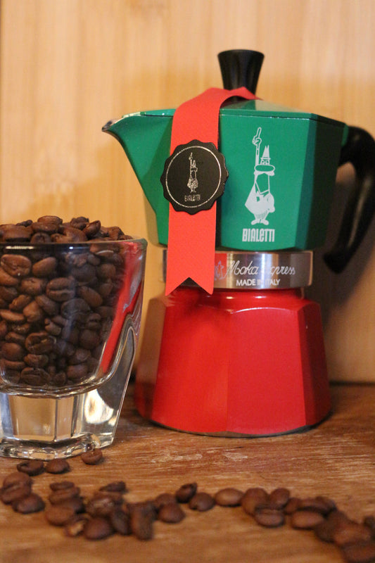 Cafeteira italiana Moka com café fresco sendo servido em xícara  branca sobre mesa de madeira rústica