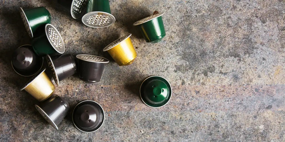 Cápsulas de café coloridas em alumínio espalhadas sobre superfície de pedra