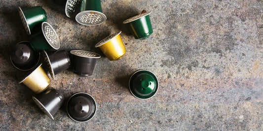Cápsulas de café coloridas em alumínio espalhadas sobre superfície de pedra