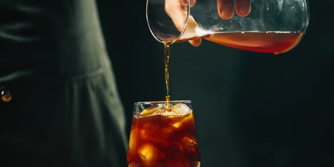 Concentrado de cold brew sendo despejado sobre gelo em um copo