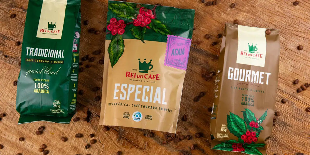 Pacotes de café Tradicional, Especial e Gourmet Rei do Café sobre mesa de madeira, com rótulos de torra, moagem e peso visíveis.