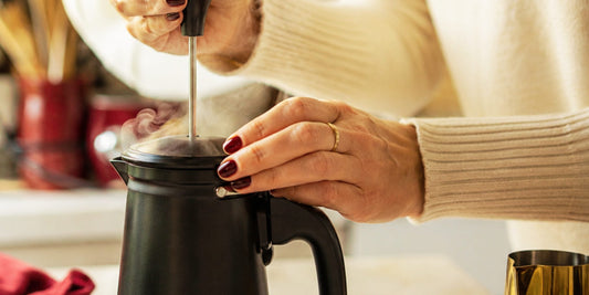 Mãos acionando o êmbolo da cremeira Bialetti Tuttocrema para fazer espuma de leite