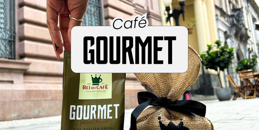  Embalagem do Café Gourmet Rei do Café sendo segurada, com saco de juta decorativo ao lado, em cenário urbano de Santos