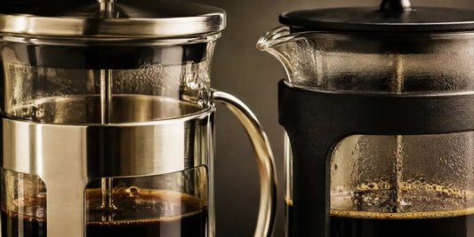 Detalhe do aço inox e da estrutura preta de duas prensas francesas com café recém-preparado