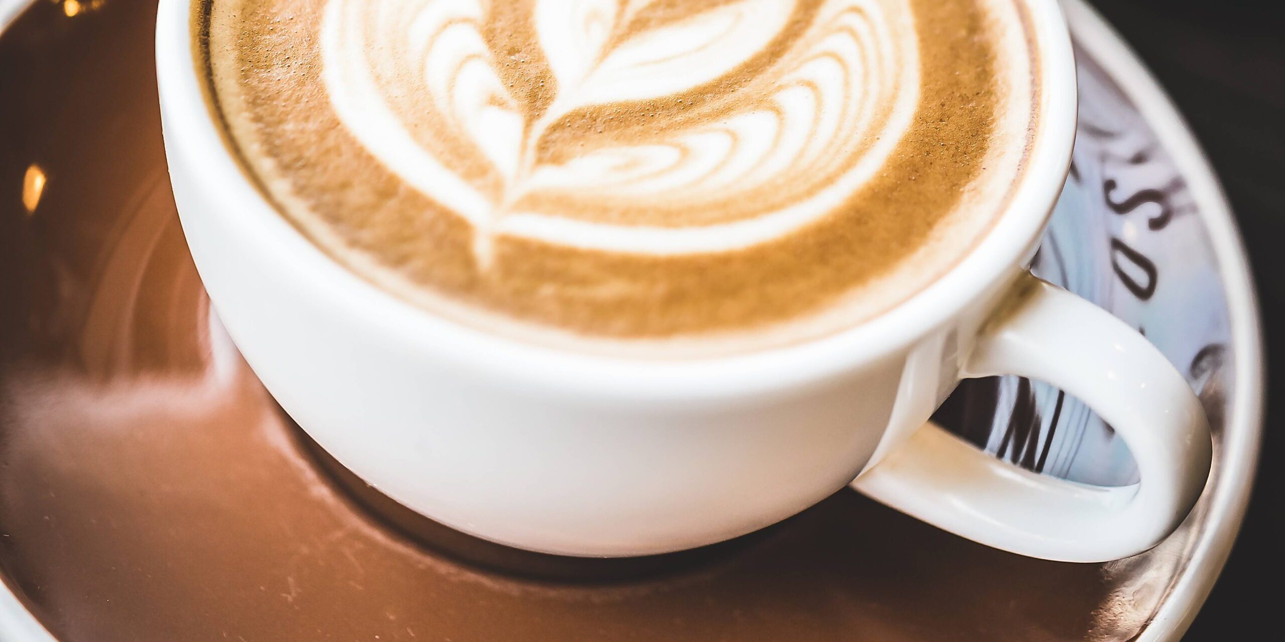 imagem de uma xícara de café com uma flor desenhada na bebida