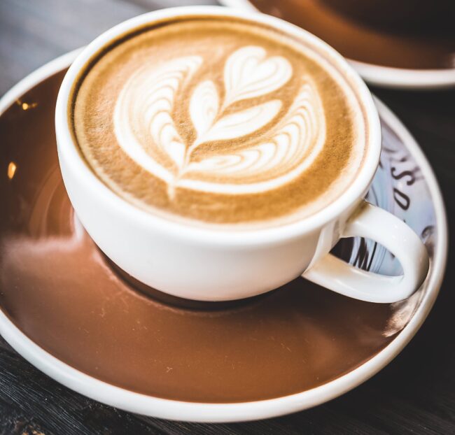 imagem de uma xícara de café com uma flor desenhada na bebida