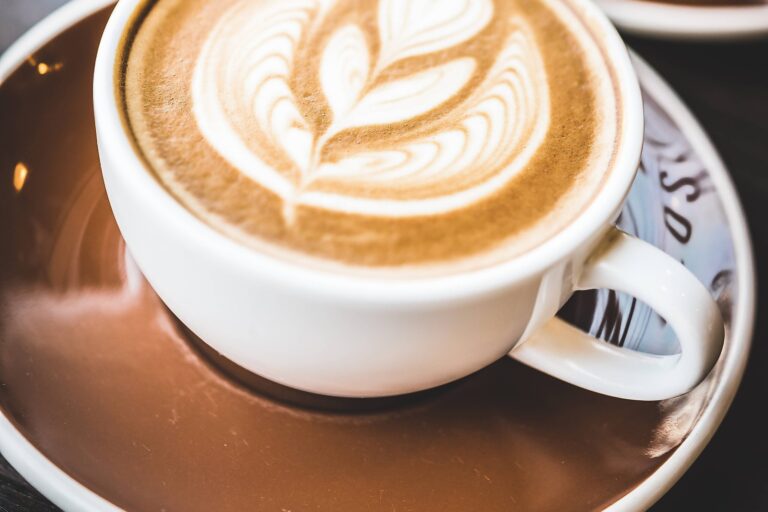 imagem de uma xícara de café com uma flor desenhada na bebida