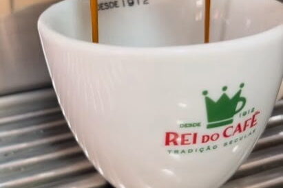 Imagem de uma xícara branca com a logo do Rei do Café que participou do 8º festival Santos Café