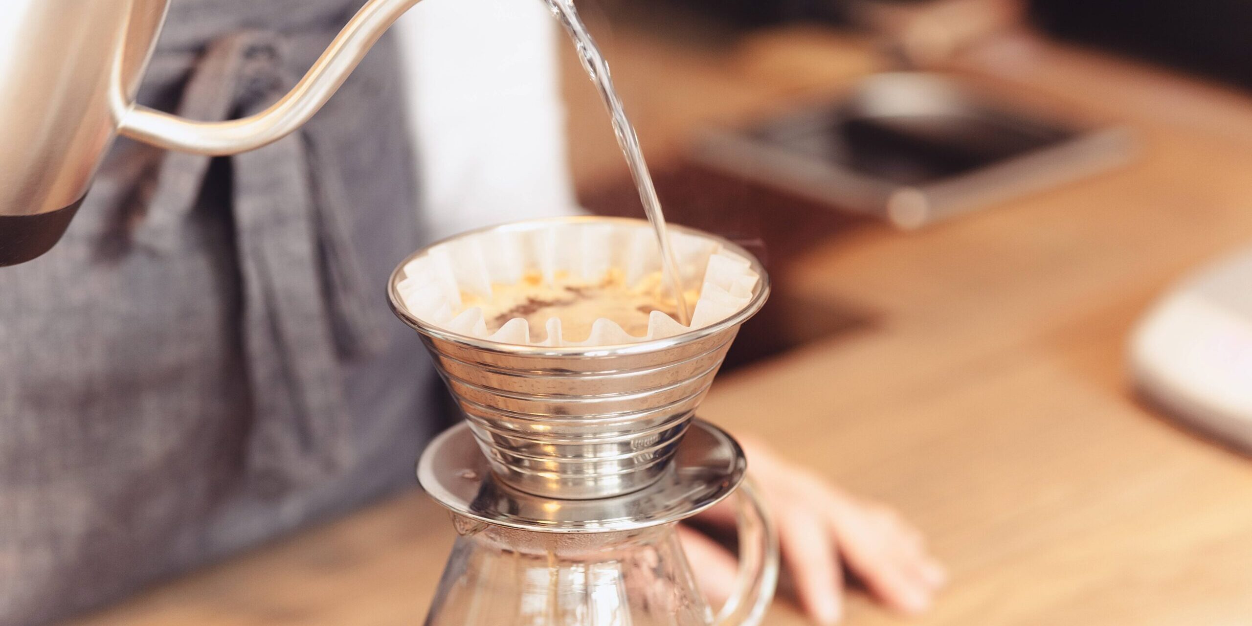 imagem de uma chaleira saindo água e caindo a água num filtro com pó de café em alusão a água para fazer café